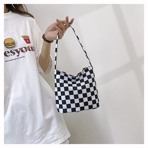 Gros plan d'un sac cabas en toile à damier noir et blanc avec une longue bandoulière