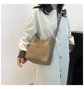 Detail of khaki leather bucket bag showing soft pebbled texture and wide shoulder strap