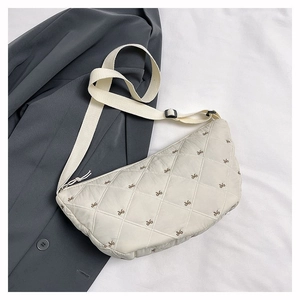 Detail der gesteppten beige Halbmondtasche mit feinen braunen Schleifen-Stickereien