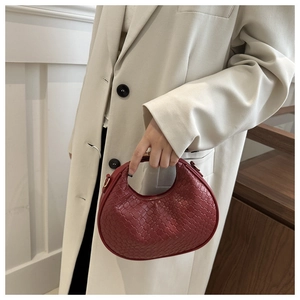 Détail du sac demi-lune en cuir tressé rouge avec boucle métallique et crochet de bandoulière