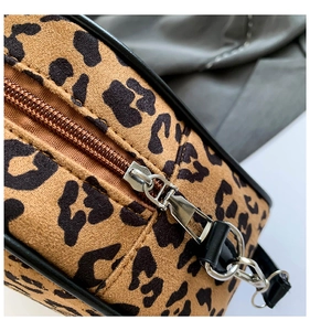 Detailed macro view of leopard print bag showing silver metal zipper and black trim edge