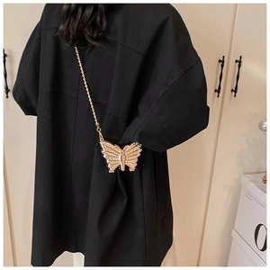 Chic butterfly mini clutch bag with gold chain strap shown on a black oversized coat