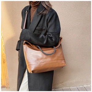 Detailed view of brown leather tote bag with unique black and white woven knot handle