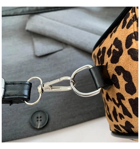 Close-up of silver metal hooks and black leather strap on leopard print handbag