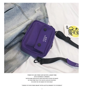 Detail of purple canvas crossbody bag with front pocket and DCY logo on blue denim background