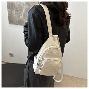 Detailed back view of white multi-pocket nylon chest bag worn over a black jacket