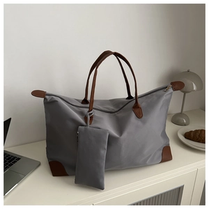 Detail of grey nylon tote bag with brown leather handles and matching small zip pouch