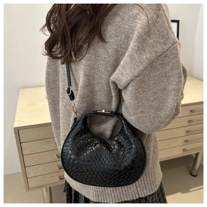 Détail du sac croissant tressé noir avec fermoir doré et bandoulière réglable