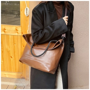 Detail of caramel brown tote bag with black rope handles and large capacity design