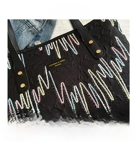 Détail d'un grand sac cabas noir matelassé avec broderie ondulée et rivets dorés
