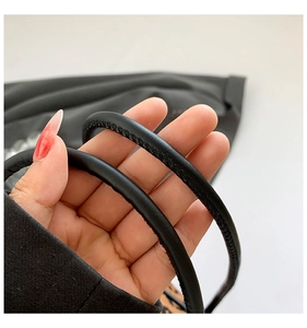 Detail of premium black leather handles with precise stitching on a leopard print handbag