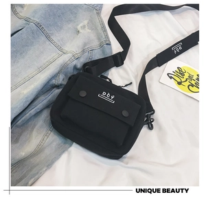 Detail of black street style canvas crossbody bag with adjustable strap and flap front pocket