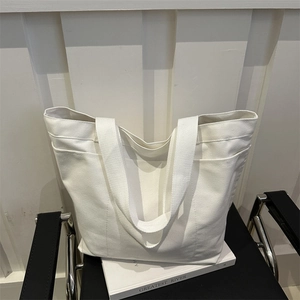 Minimalist white canvas tote bag with side pockets on a chair, high-capacity shoulder bag