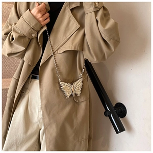 Close-up of butterfly mini bag with pearls and rhinestones on a khaki trench coat