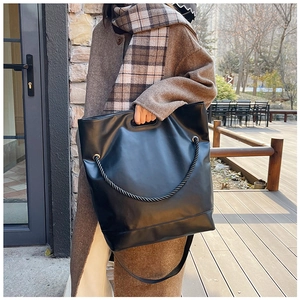 Close-up of black leather tote bag with unique thick rope strap in an outdoor setting