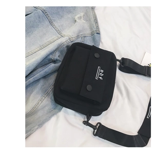 Detailed close-up of a black canvas crossbody bag with DCY logo and adjustable strap