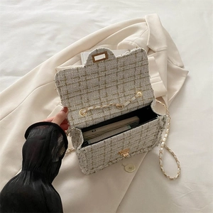 Detail of tweed crossbody bag showing interior space for wallet and phone on beige blazer