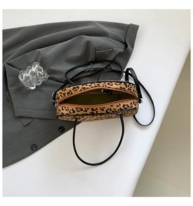 Top view of leopard print tote bag with black handles and adjustable strap on a gray blazer