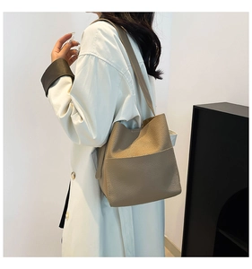 Detail view of khaki pebbled leather bucket bag with long shoulder strap in a minimalist style