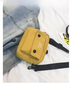Detail view of yellow canvas crossbody bag with black buckle buttons and DCY logo
