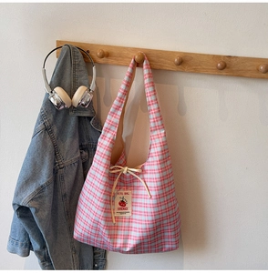 Detail of pink and blue checkered canvas tote bag with tomato patch on a wall hook