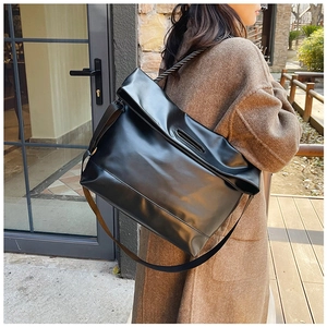 Detail of glossy black large tote bag showing wide shoulder strap and PU leather texture