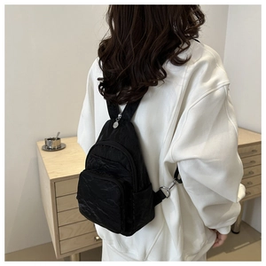 Detail of a versatile black nylon backpack with multiple zipper pockets on a model
