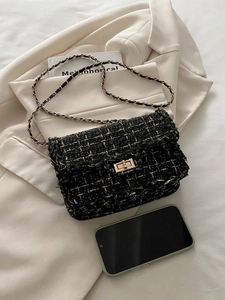 Detail of black tweed crossbody bag with gold chain strap and metal turn-lock closure