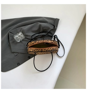 Top view of leopard print handbag with black handles and interior zipper detail