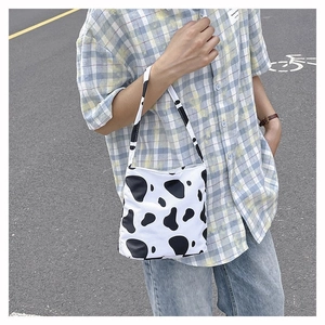 Détail du motif imprimé vache sur un sac à bandoulière en tissu noir et blanc tendance