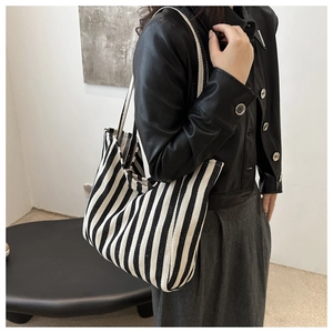 Close-up of a striped canvas tote bag worn by a model in a minimal urban style