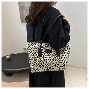 Detail view of large leopard print tote bag with black leather straps and premium canvas texture