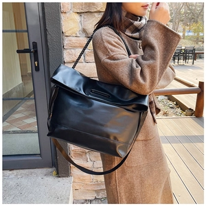 Detail of black PU leather shoulder bag with unique twisted rope handle in a winter street setting