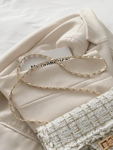 Detail of white and gold tweed fabric with metallic turn-lock and chain strap