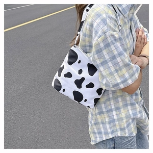 Gros plan du sac à bandoulière décontracté en toile à motif de vache noir et blanc