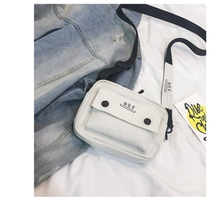 Detailed macro view of white canvas crossbody bag with black DCY logo and buckles