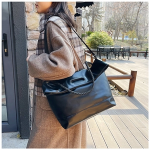 Detail of black leather tote bag with metal grommets and thick rope handle in street style