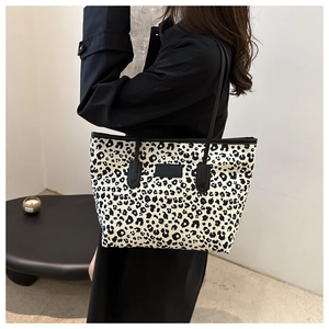 Close-up of leopard print canvas tote bag with black leather patch and slim shoulder straps