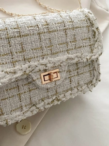 Detail of tweed woven bag featuring golden metal twist lock and classic chain strap