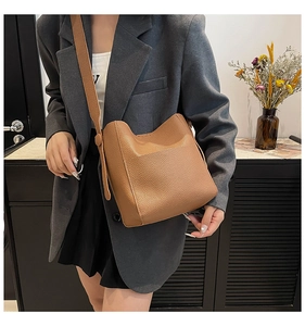 Detailed macro view of brown lychee grain leather tote on model with shoulder strap