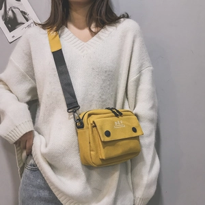 Detail of bright yellow canvas crossbody bag featuring DCY logo and black buckles
