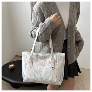 Détails de broderie linéaire colorée et rivets dorés sur un sac cabas blanc chic