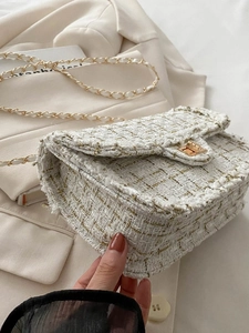 Detailed close-up of white and gold tweed chain bag with elegant gold rotating metal clasp