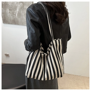 Rear view of a model wearing the large black and white striped canvas tote bag