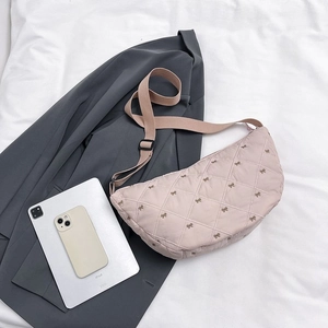 Detailaufnahme der gesteppten Halbmond-Tasche mit Schleifenstickerei und Trageriemen