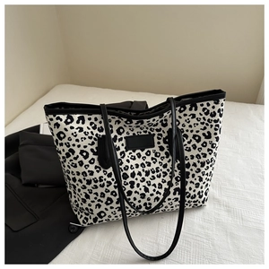 Close-up of leopard print tote bag featuring black leather patch on white fabric