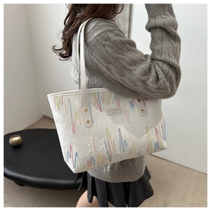Vue détaillée du sac cabas blanc avec broderies ondulées colorées et rivets dorés