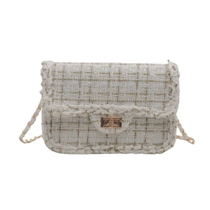 Detailed close-up of white tweed crossbody bag with gold chain strap and turn-lock closure