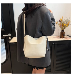 Detailed back view of off-white leather bucket bag worn with a gray suit for work