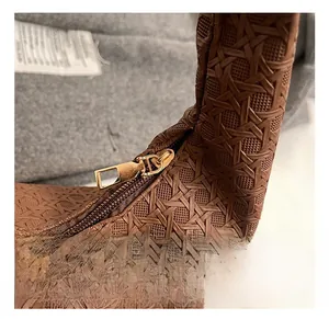 Close-up of woven brown leather texture and premium gold zipper detail on crescent bag